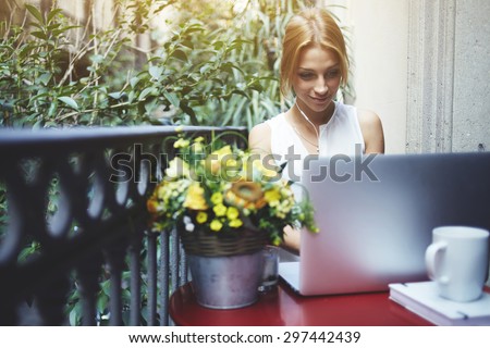 Creative young woman work on laptop during breakfast on her terrace, experienced female freelancer sitting at red balcony table front open computer, student girl working on a wireless net-book at home