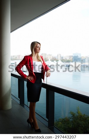 Successful businesswoman in corporate clothing standing on the balcony terrace with beautiful marina view while relaxing the open air, confident female entrepreneur thoughtfully look into the distance