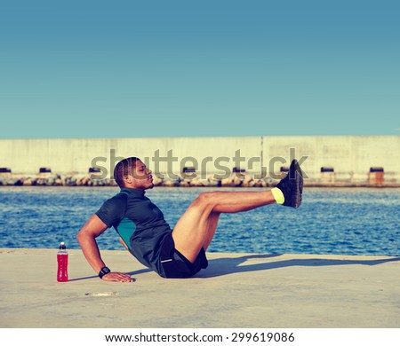 Muscular build man doing hard legs exercise before start his run at sunny afternoon outdoors,afro american sports man working out at copy space area for your text message on advertising content on top