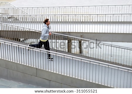 Full length portrait of male runner jogging fast down the bridge with copy space area for your text message or advertise content, male runner working out outdoors and listening to music in headphones