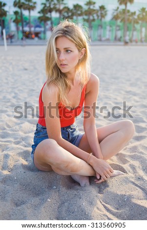 Young beautiful woman alone enjoying summer afternoon on the beach, gorgeous female relaxing during summer holidays at sea, stylish hipster girl posing for the camera at seashore