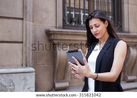 Portrait of a lost female tourist using digital tablet for navigation while walking in urban setting during summer holidays, pretty latin woman browsing internet on her touch pad during strolling