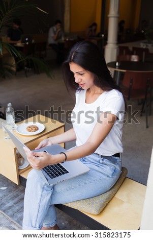 Portrait young pretty woman having video conference on her laptop computer while sitting in restaurant during breakfast,female freelancer working on her net-book while sitting in cafe in the fresh air