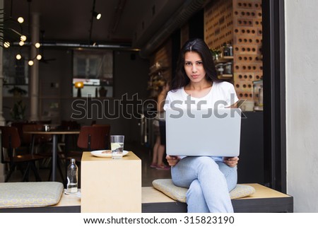 Young latin woman sitting with open laptop computer in modern coffee shop in the fresh air, female freelancer using net-book for her distance work, student girl learning via portable gadget device