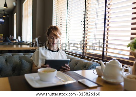 Portrait of beautiful female student listen or studying on-line training course in headphones while using her digital tablet,charming young woman have video conversation while breakfast in coffee shop
