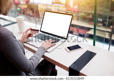 Photo of Cropped image of female freelancer using online banking service to transfer money from credit card using modern laptop computer with mock up monitor connected to free wifi sitting in coffee shop
