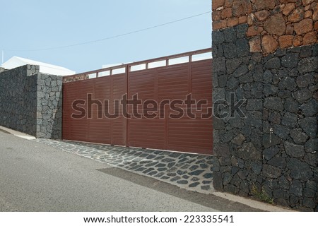 Modern garage door. Large automatic sliding garage door. Walls made of volcanic rock. Entrance to wealthy residence on island Lanzarote.