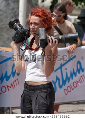 CORTINA, ITALY - JUNE 30, 2012: Photo showing a red-haired photographer on the finish line of the Lavaredo Ultra Trail in the Cortina d\'Ampezzo.