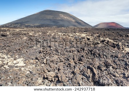 Lanzarote volcanic landscape; Chaotic volcanic rocks in the foreground and red Montana Colorada in the background on the right.
