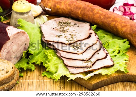 Sausages and slices of sausage arranged with cup of coffee vegetables, spices and bread for breakfast or dinner on cutting board and bamboo mat. Food arrangement.