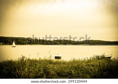 Landscape stylized on vintage with boats for fishing on the lake at the shore. Vintage photo. Nature background. Tranquil landscape.