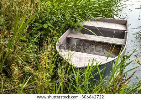 Photo of old boat for fishing on the lake at the shore among the reeds. Outdoor wedding theme. Theme of vacation, holiday, leisure and relax.