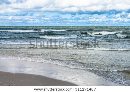 Landscape of rough sea with waves and cloudy sky. Baltic sea coast near Leba in Poland.