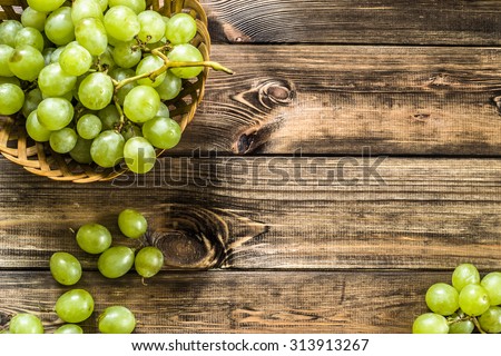 Bunch of green grapes in the basket, fruits of autumn, a symbol of abundance on rustic wood background with copy space, top view, close-up.