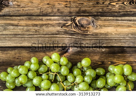 Bunch of green grapes, fruits of autumn, a symbol of abundance on rustic wood background with copy space, top view, close-up.
