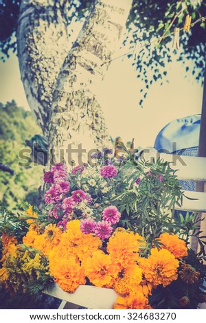 Bunch of flowers on a white chair on a blurry garden background, vintage photo.