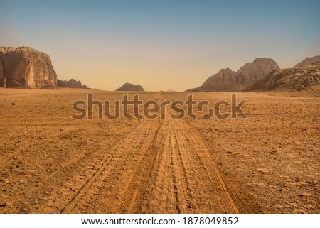 Dramatic view of the endless valley road, Wadi Rum desert, Jordania. Spectacular clear sky with yellow horizon line, mountain range, lots of red sand and extremely arid, dry terrain in the background. Foto stock © 
