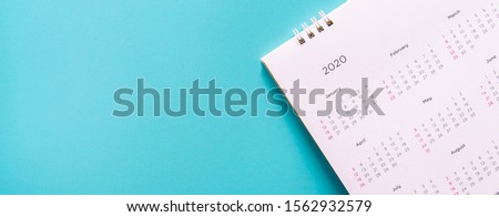 close up top view on white calendar 2020  month schedule to make appointment meeting or manage timetable each day lay on teal background for planning work and life concept