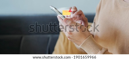 close up employee man hand holding smartphone to checking alert from mailbox with warning sign for email spam security and protection system technology concept