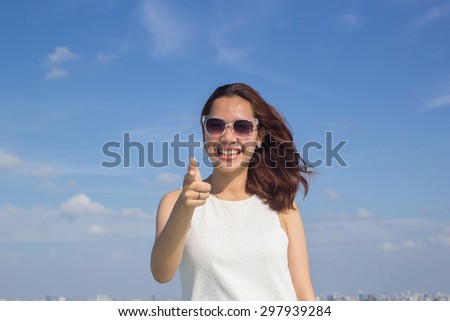 close up happy woman smiling and pointing at the camera  over blurred blue sky backgrounds.selective focused,soft focused.