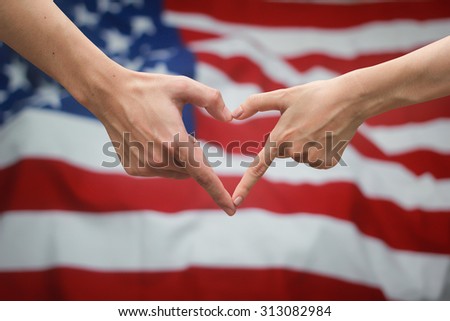 close up male and female hands making heart on blurred crumpled retro USA flag vignette backgrounds . Labor day concept ,soft focused.