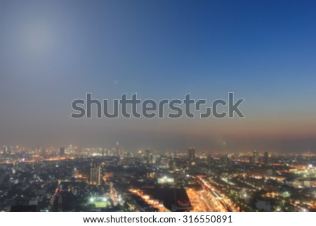 Blurred night city backgrounds : blur of night city town with sunset and twilight sky and bokeh light view form roof top of building . blur backgrounds concept