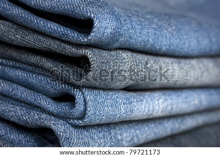A pile of different types of blue denim jeans closeup