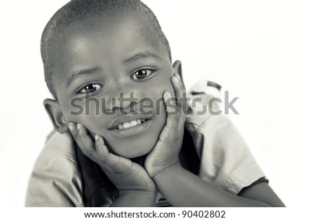 Cute 3 year old black or African American boy in black and white smiling with his hands on his chin