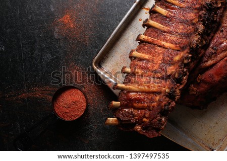Dark and moody rack of meaty baby back ribs with spicy dry rib rub seasoning on a worn metal sheet pan Stock foto © 