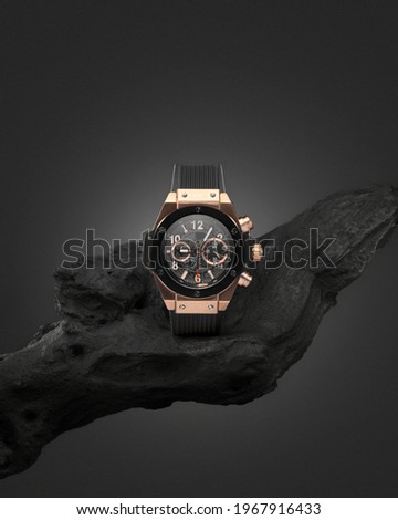 Beautiful gold men's watch with a black strap on a wooden stand, on a gray background. Beautiful gold watch. A luxury brand watch 商業照片 © 