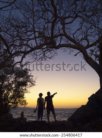 silhouette loving couple holding hands at beach during sunset