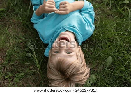 Similar – Image, Stock Photo A cheerful boy with a phone in his hands is sitting in a chair and playing a game or watching cartoons.