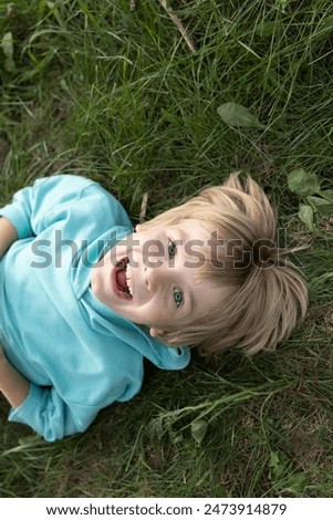 Similar – Image, Stock Photo A cheerful boy with a phone in his hands is sitting in a chair and playing a game or watching cartoons.