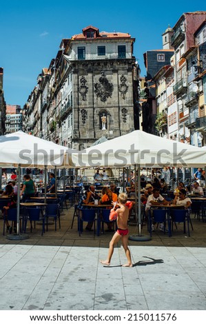 PORTO, PORTUGAL - AUGUST 6: A kid walks in front of tourists after a bath in Douro River on August 6th, 2014 in Porto, Portugal.