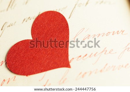 A single red heart shape on a handwritten old journal.
