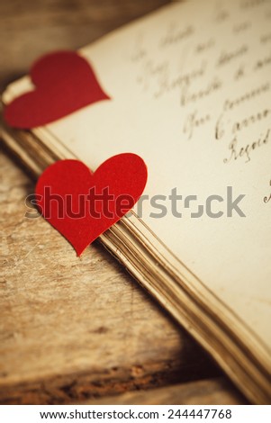 A couple of red heart shapes on a handwritten old journal.