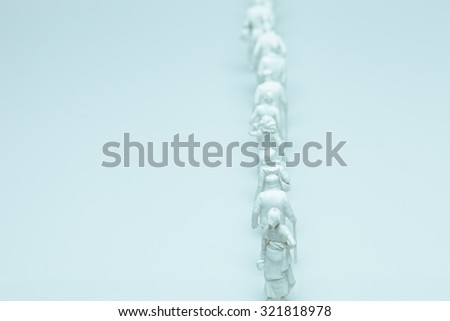Queue of white figurines walking representing migration, refugees, citizenship and displaced people issues.