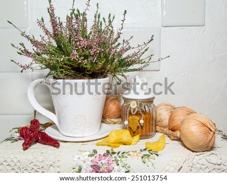 still life with flower, onions, chili peppers on the kitchen wall background