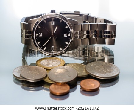 Men\'s wrist watch and metal coins. reflection. close-up. Macro.