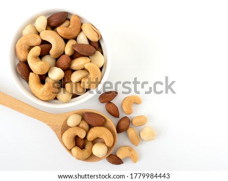 Nuts in top view circle shaped ceramic bowls and nuts on top view wooden spoon isolated on white background. Various nuts (almonds, macadamia, cashew, peanuts). Mix nut healthy ingredients food.