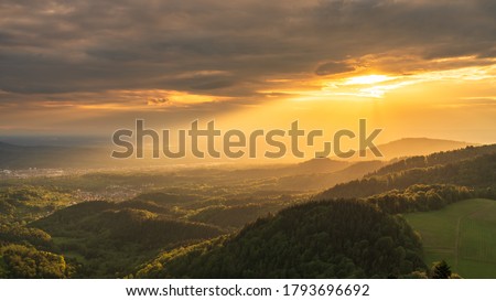 Foto Bild Dämmerstunde. Die Sonne geht hinter einer Baumgruppe, mit schönen Farben unter.