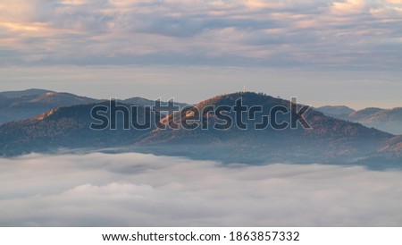 The first sunrays hit the top of the mountain Merkur while the valley is covered by an inversion Stock foto © 