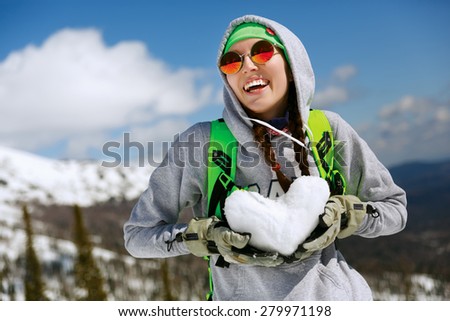 Winter sport, snowboarding - portrait of young snowboarder girl With snow heart in hands