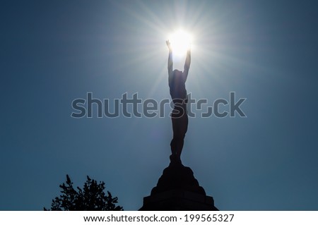Icarus backlit statue holding the sun