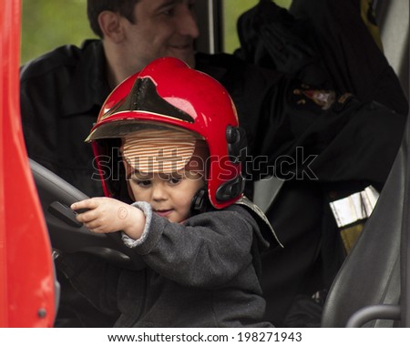 SZCZECIN, POLAND - MAY 29, 2014: Veterans Day in Poland. Child in a fireman\'s helmet.Boy playing with the steering wheel in the Fire Truck.