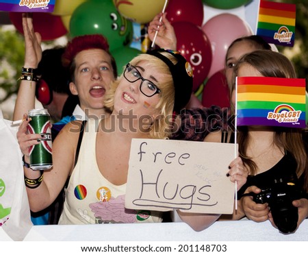 BERLIN, GERMANY - JUNE 21, 2014: Christopher Street Day.Happiness young woman offer free hugs  Crowd of people Participate in the parade celebrates gays, lesbians, bisexuals and transgenders.