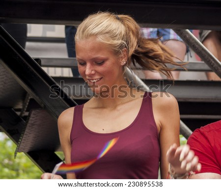BERLIN, GERMANY - JUNE 21, 2014: Christopher Street Day. Crowd of people Participate in the parade celebrates gays, lesbians, and transgenders. Prominent in the image, Attractive woman dancing.