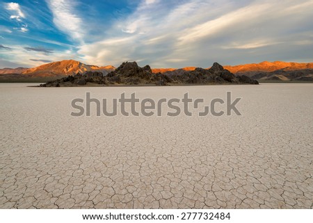 Dry lake bed on sunset, with cracked mud on a lake floor blue sky, clouds and mountains. Racetrack Playa. Death Valley national park. California. USA.