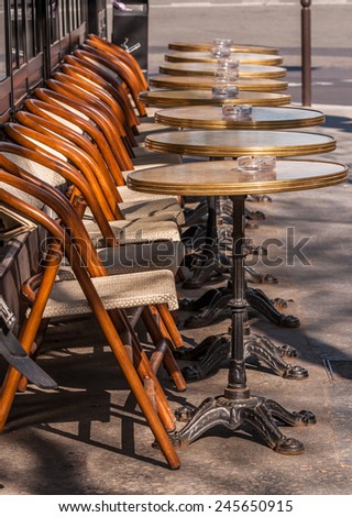 Tables and chairs are unoccupied outside a bistro in Paris France.