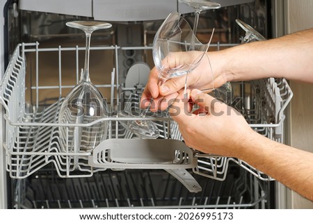 Broken wine glass in the dishwasher after washing. hand holds a broken glass in front of an open dishwasher. glasses breaking in the Dishwasher